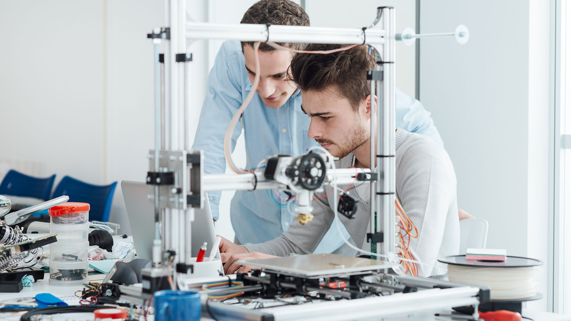 A modern 3D printer is the focal point in a bright, collaborative workspace.