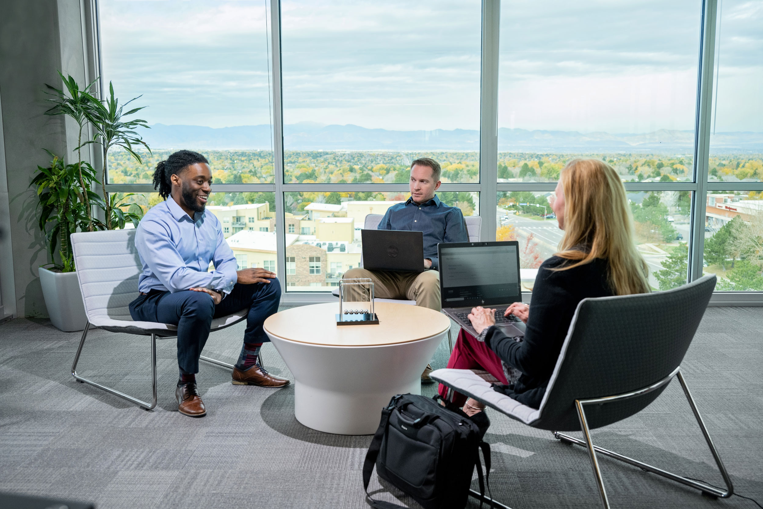 Three_People_Meeting_With_Notebook_In_Front_Of_Window