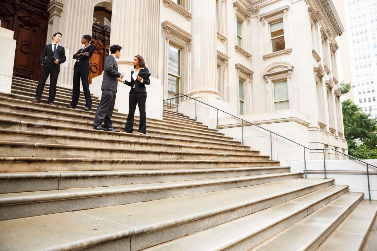 Four professionals talking on steps of a building