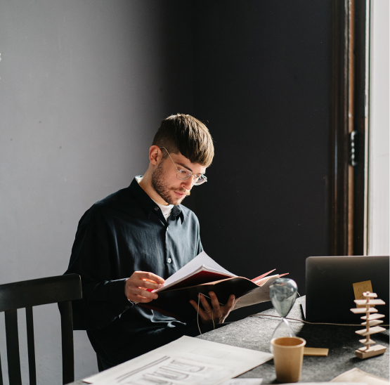 Thoughtful Man in Glasses Reading at Desk Thoughtful Man in Glasses Reading at Desk