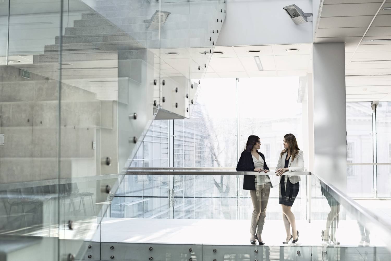 Businesswomen_Conversing_on_Railing Businesswomen_Conversing_on_Railing